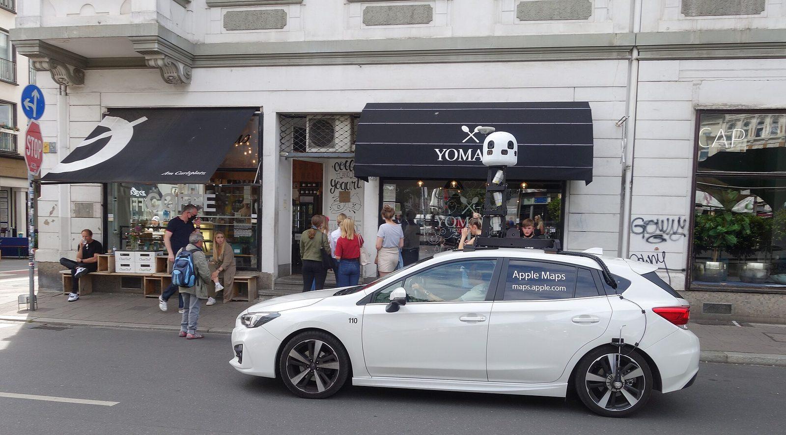 An Apple Maps survey vehicle parked on a street in Düsseldorf, with a roof-mounted sensor mast carrying cameras and LiDAR