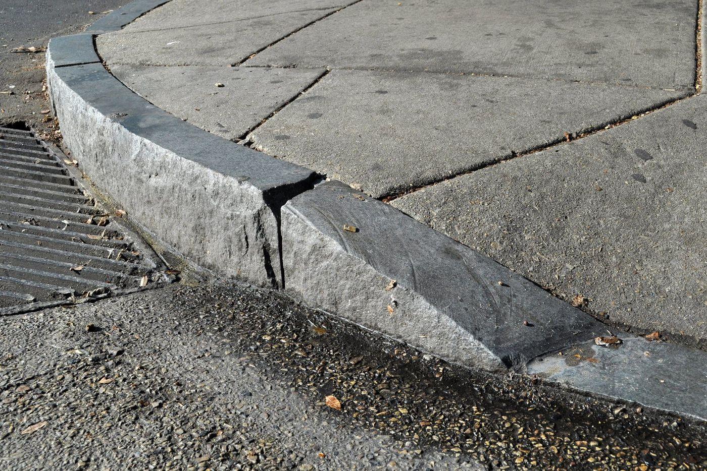 Close-up of a stone kerb ramp at a street corner, with a visible lip where the ramp meets the carriageway